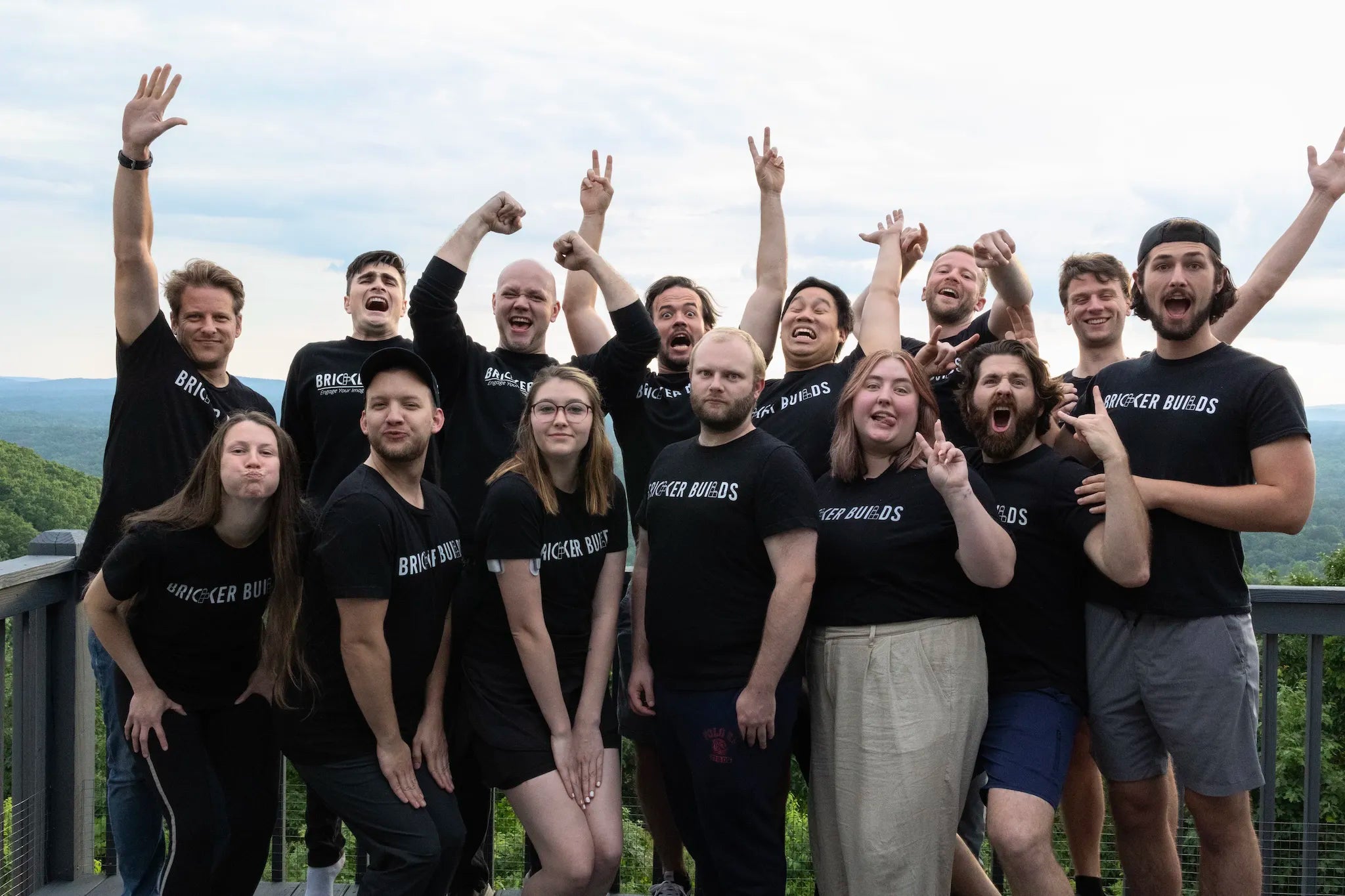 Bricker Builds team wearing team tee shirts posing for a picture with hands raised in the mountains on a porch in 2023