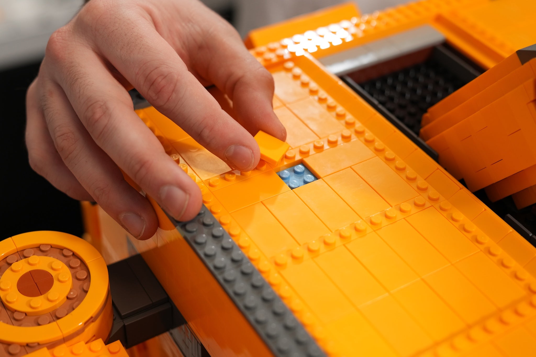 Hand interacting with a large orange building brick hobby assembly of Scrap-E by Bricker Builds