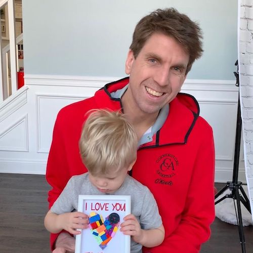 super lego dad holding child on his lap with card that reads I love you with a lego heart