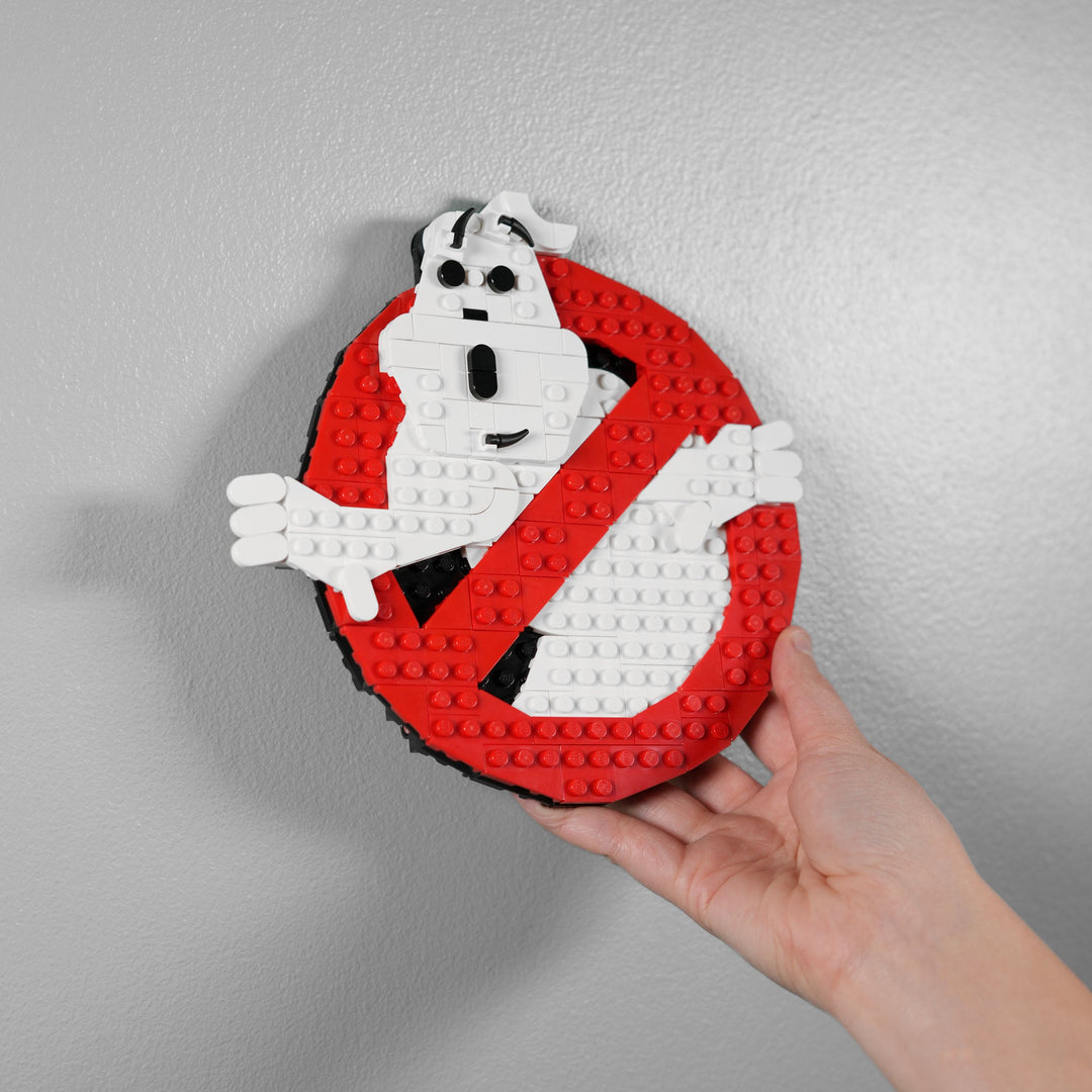 Ghost Hunters Logo made of LEGO® Bricks by Bricker Builds being hung on the wall with a heand
