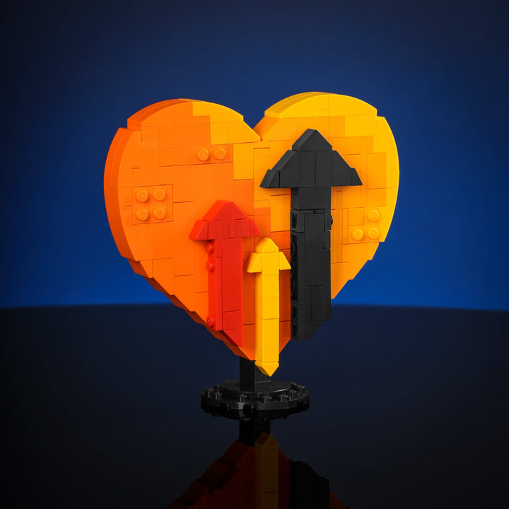 Heart-shaped object for Stand Up to Cancer campaign made of interlocking bricks with arrows on a blue background by Bricker Builds